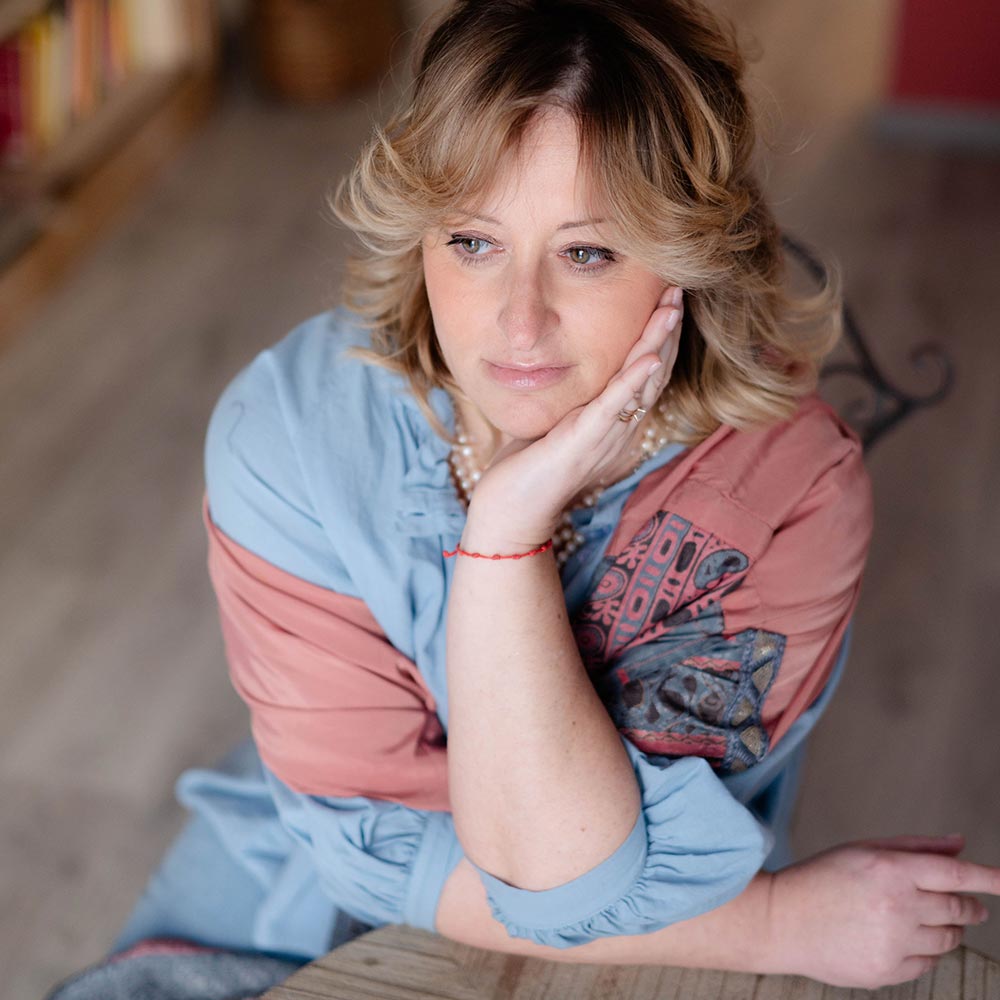 Uno spazio dell’anima – Studio Malvarose a Pistoia Lisa Guastini, psicoterapeuta, seduta alla scrivania nello studio Malvarose a Pistoia, con libri e luce calda a creare un’atmosfera accogliente.